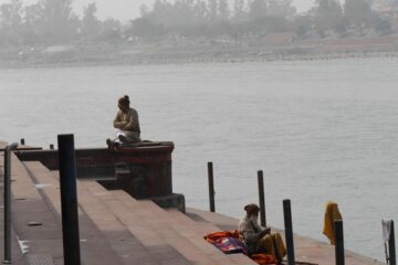 Sitzende Menschen an den Treppenstufen zum Ganges