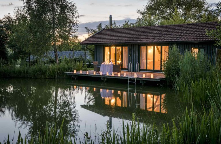 Innen beleuchtetes Haus mit Terrasse am See bei Kerzenschein