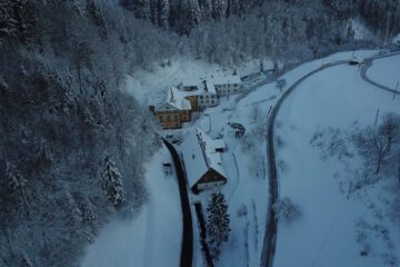 Blick ins verschneite Tal und das Meditationszentrum