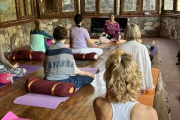 Gruppe von Menschen, die gemeinsam Yoga in einem Raum ausüben.