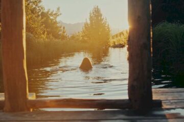 Frau schwimmt in einem kleinen See mit Bergblick