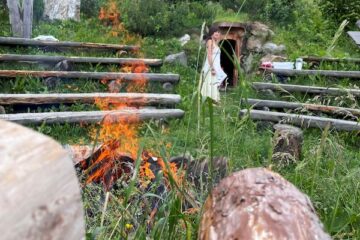 Frau in einer Wiese mit Steinen und Feuer